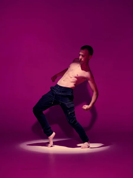Guay joven bailarín con torso desnudo bailando en estudio en luz rosa en el centro de atención. Escuela de baile cartel —  Fotos de Stock