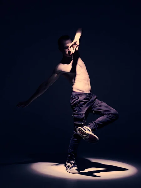Fresco ballerino ragazzo con torso nudo ballare in studio sotto i riflettori su sfondo nero. Annuncio gare di battaglia — Foto Stock