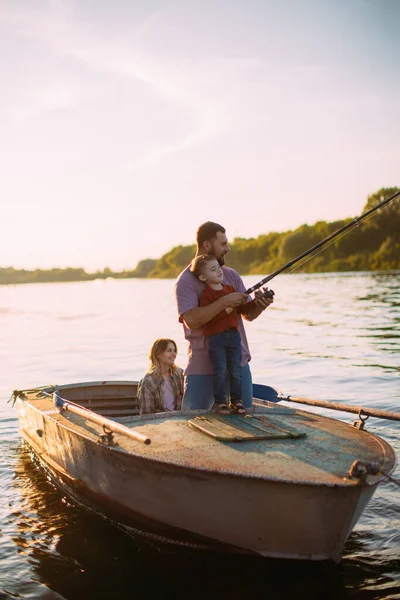 Feliz pesca familiar en barco en el río en verano. Padre enseña a pescar. Foto para blog sobre viajes en familia —  Fotos de Stock