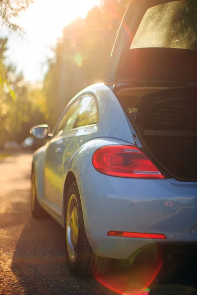 Rear side view of car in sunlight on the path with opened trunk. Photography about travelling