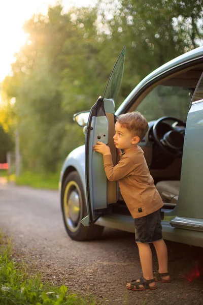 Cute baby boy small driver standing near the car in sunlight. Summertime photography for ad or blog about family trip