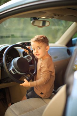 Gülümseyen bebek direksiyonu tutan küçük şoför. Aile gezisiyle ilgili reklam veya blog fotoğrafları