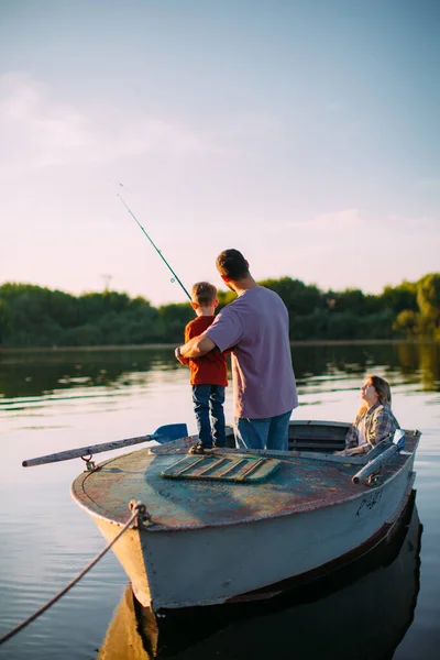 夏天，年轻的家人在船上钓鱼。父亲教儿子钓鱼。后视镜有关家庭旅行的博客照片 — 图库照片