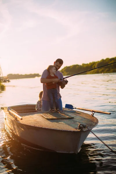 Joven pesca familiar en barco en el río en verano. Padre enseña a pescar. Foto para blog sobre viajes en familia —  Fotos de Stock