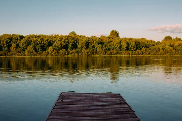 Деревянный пирс без людей на спокойном озере или реке. Летняя пейзажная фотография — стоковое фото
