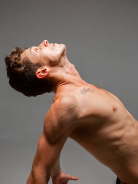 Gri arka planda çıplak gövdesi olan şık saç kesimi olan yakışıklı bir gencin portresi.