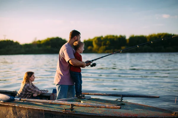 Jeune pêche familiale en bateau sur la rivière en été. Père enseigne la pêche fils. Photo pour blog sur les voyages en famille — Photo