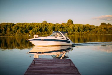Sükunet göl ya da nehir kıyısındaki rıhtımın yakınındaki eğlence teknesi denize açılır. Yaz dönemi manzara fotoğrafçılığı