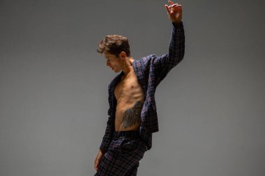 Yakışıklı genç adam ve takım elbiseli dansçı stüdyoda gri arka planda izole edilmiş modern anlamlı dans.