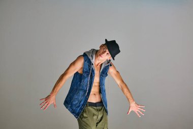 Stüdyoda hip-hop dansı yapan break dansçı çocuk gri arka planda izole edilmiş. Dans okulu posteri