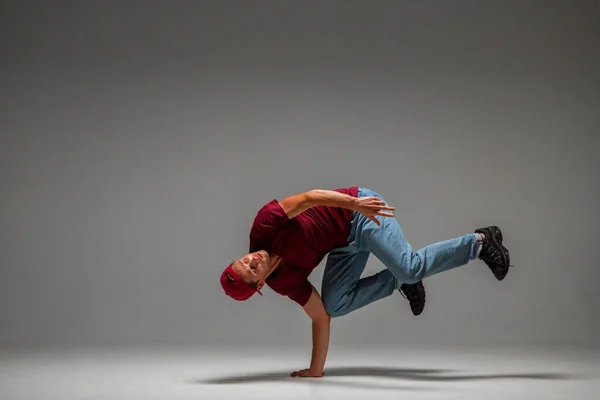 Fajny facet breakdancer taniec niższe break dance na podłodze odizolowany na szarym tle. Lekcje tańca break dance — Zdjęcie stockowe