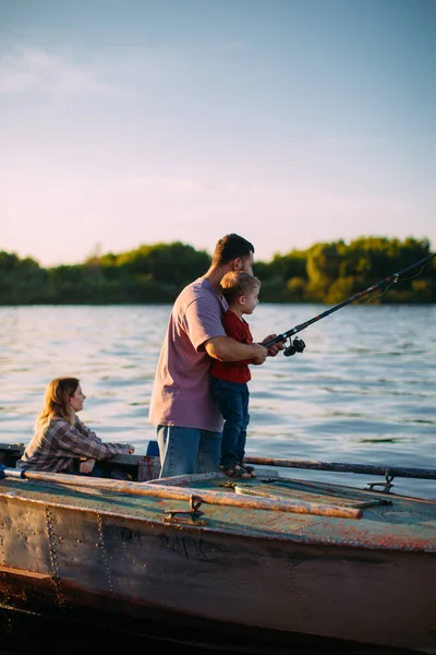 Padre enseña a su hijo a pescar en barco en el río en verano. Foto para blog sobre viajes en familia —  Fotos de Stock