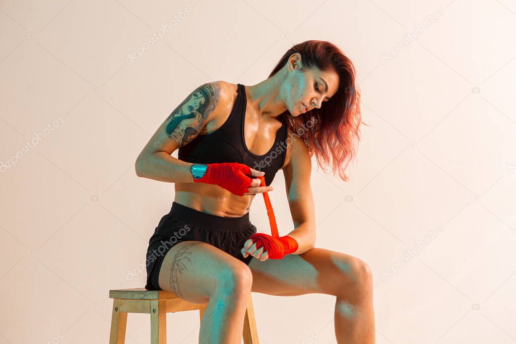 Beautiful sexy girl fighter putting on boxing bandages in studio in neon light. Mixed martial arts poster