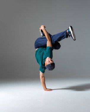 Havalı break dansçı çocuk gri arka planda izole bir şekilde stüdyoda yerde dans ediyor. Breakdance okulu posteri