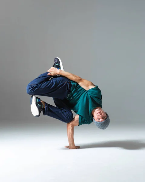 Stylowy b-boy tańczący na podłodze w studio odizolowanym na szarym tle. Plakat szkoły breakdance — Zdjęcie stockowe