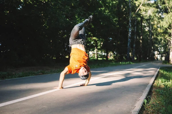 Молодой парень-брейкдансер танцует на дороге в парке летом. Плакат школы брейк-данс — стоковое фото