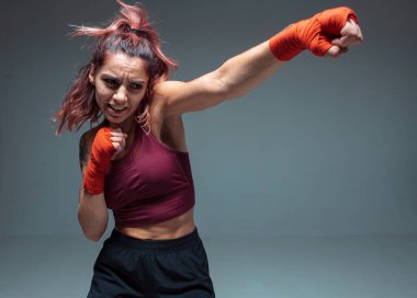Stüdyodaki güzel bayan boksör gri arka planda izole edilmiş. Karışık dövüş sanatları posteri