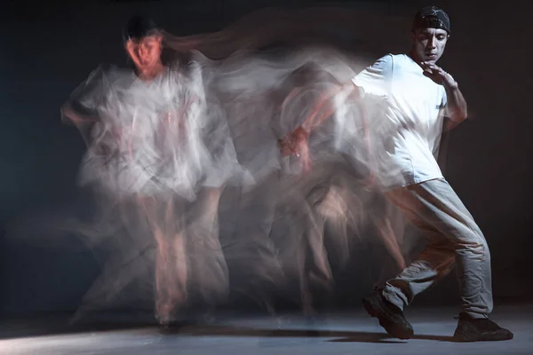 Jeune breakdancer élégant dansant en studio sur fond noir. Longue exposition. Concours de bataille annonce — Photo