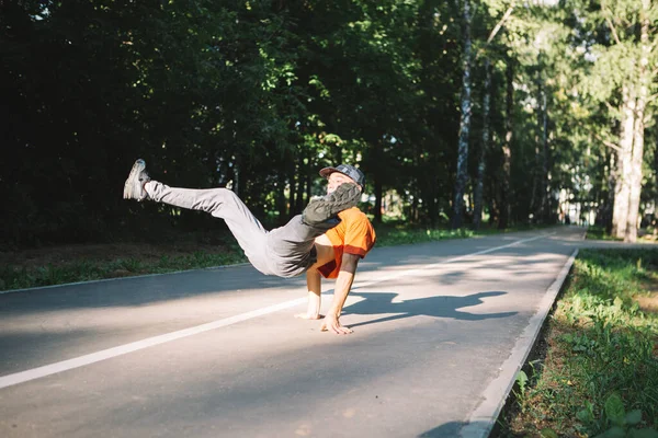Крутой молодой парень танцует брейк-данс на дороге в парке летом. Плакат школы брейк-данс — стоковое фото