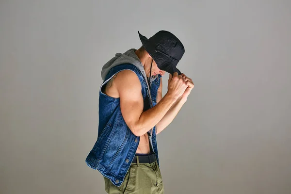 Joven chico breakdancer en hat dancing hip-hop en estudio aislado sobre fondo gris. Escuela de baile cartel — Foto de Stock