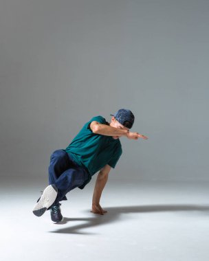 Gri arka planda izole bir şekilde break dans yapan havalı break dansçı. Breakdance posteri