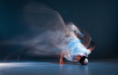 Şık bir break dansçı, neon ışıkta yerde hip-hop yapıyor. Dans okulu posteri. Uzun pozlu çekim