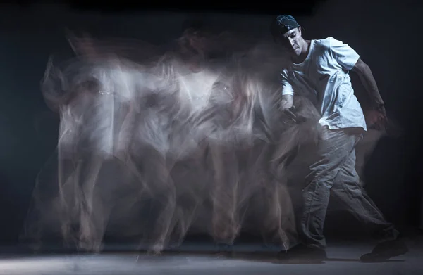 Elegante ragazzo breakdancer ballare hip-hop in studio su sfondo nero. Colpo a lunga esposizione — Foto Stock