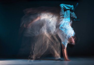 Genç break dansçı, neon ışıkta hip-hop dansı yapıyor. Dans okulu posteri. Uzun pozlu çekim