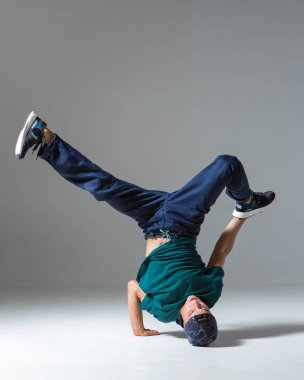 Yerde dans eden sporcu break dansçı gri arka planda tek başına. Breakdance posteri