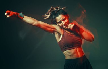 Rahatlatıcı karın kasları olan havalı kız stüdyoda neon ışıkta yumruk atıyor. Spor ve motivasyon konsepti. Uzun pozlu çekim