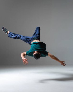 Şık genç break dansçı gri arka planda izole bir şekilde dans eden hip-hop dansçısı. Breakdance dersleri