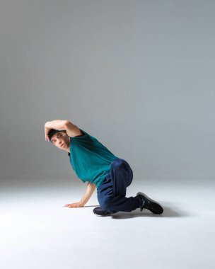 Stüdyoda break dans yapan adam gri arka planda izole edilmiş.