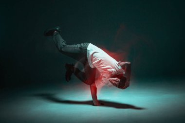 Şık genç adam neon ışıkta hip-hop dansı yapıyor. Uzun pozlu çekim. Savaş yarışması duyurusu