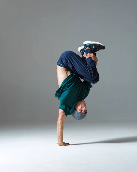 Cool guy breakdancer se para en una mano bailando danza de descanso inferior aislado sobre fondo gris. Romper clases de baile —  Fotos de Stock