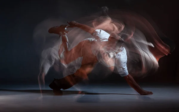 Guy breakdancer bailando hip-hop en el suelo en el estudio sobre fondo negro. Cartel de la escuela de baile. Disparo de larga exposición —  Fotos de Stock
