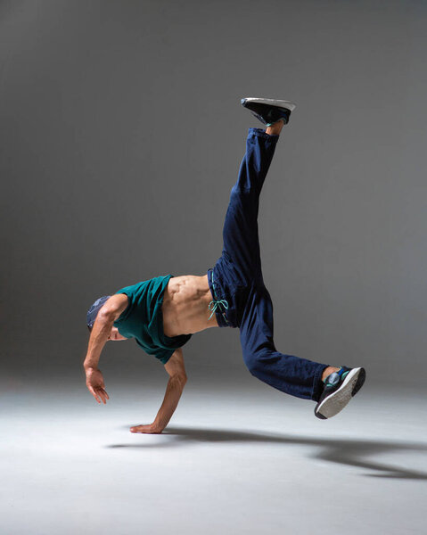 Cool b-boy dancing in studio isolated on gray background with copy space. Breakdancing school poster