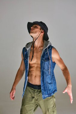 Gri arka planda izole edilmiş, çıplak vücutlu ve panama şapkalı yakışıklı bir genç.