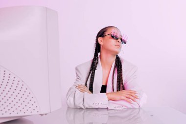Güneş gözlüklü Asyalı kadın ofis çalışanının moda portresi. Stüdyodaki masada oturan çıkartmalarla.
