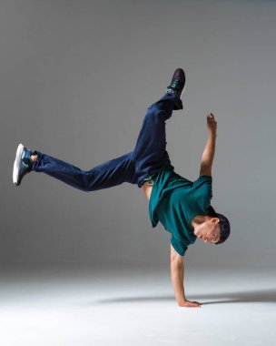 Havalı break dansçı çocuk gri arka planda tek başına stüdyoda dans ediyor. Breakdance posteri
