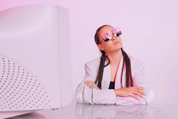 Портрет азійської жінки - офісного працівника у сонцезахисних окулярах зі наклейками, що сидять за столом з застарілим комп "ютером у неоновому світлі. — стокове фото
