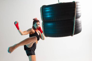 Havalı kadın boksör eğitimi stüdyoda kum torbasıyla tekmeliyor. Spor ve motivasyon kavramı