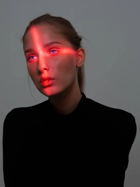 Portré fiatal csinos lány kereszt alakú piros fény az arcán szürke stúdió háttér — Stock Fotó