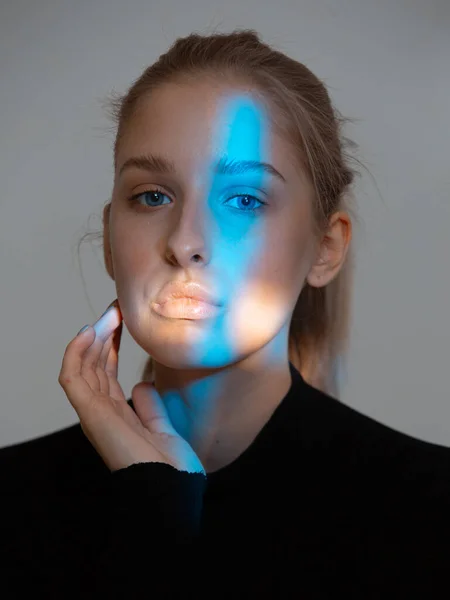 Portret van jonge mooie vrouw met een perfecte huid en een straal blauw licht op haar gezicht — Stockfoto