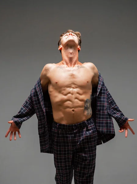 Stilig ung kille i en vidöppen jacka med naken bål stå i studio på grå bakgrund. Kropp med tatuering — Stockfoto