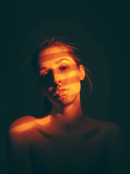 Cool portrét mladé dívky s nahými rameny a stín vzor na tváři ve studiu na černém pozadí — Stock fotografie