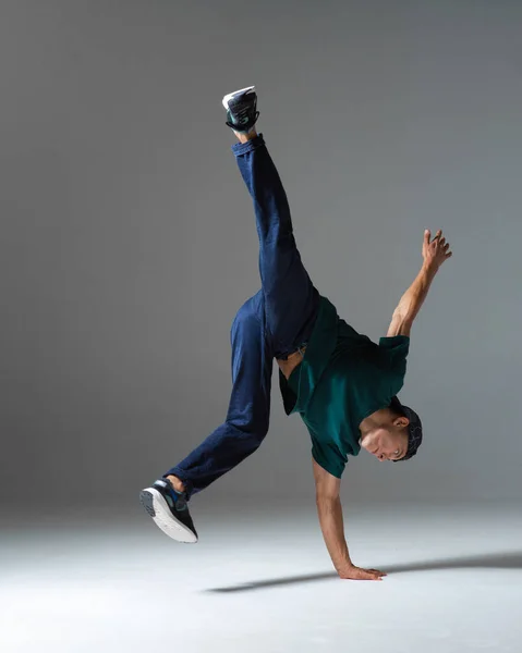 Gri arka planda tek başına duran havalı break dansçı adam dans ediyor. Breakdance dersleri — Stok fotoğraf