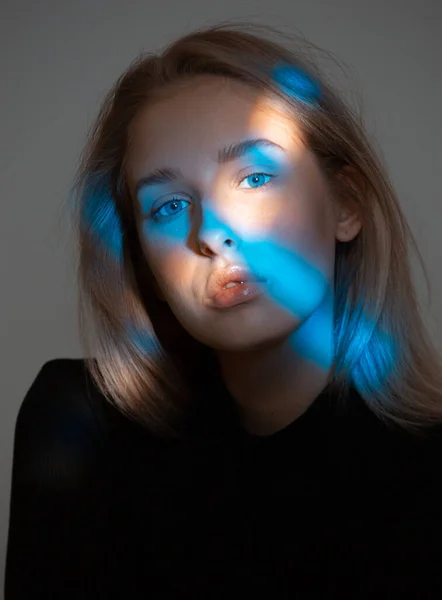 Módní krása portrét mladé dívky pózující ve studiu. Dívka s modrým světlem na tváři — Stock fotografie