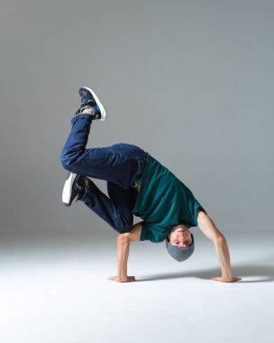 Gri arka planda tek başına dans eden şapkalı havalı break dansçı. Dans okulu posteri