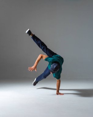 Havalı break dansçı çocuk gri arka planda tek başına stüdyoda dans ediyor. Breakdance posteri