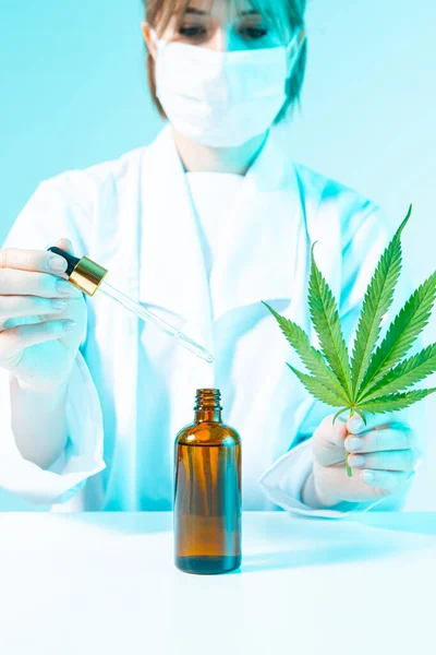 Femme scientifique tenant une feuille de chanvre, testant l'huile de cbd par pipette en laboratoire, produits du cannabis à usage médical — Photo